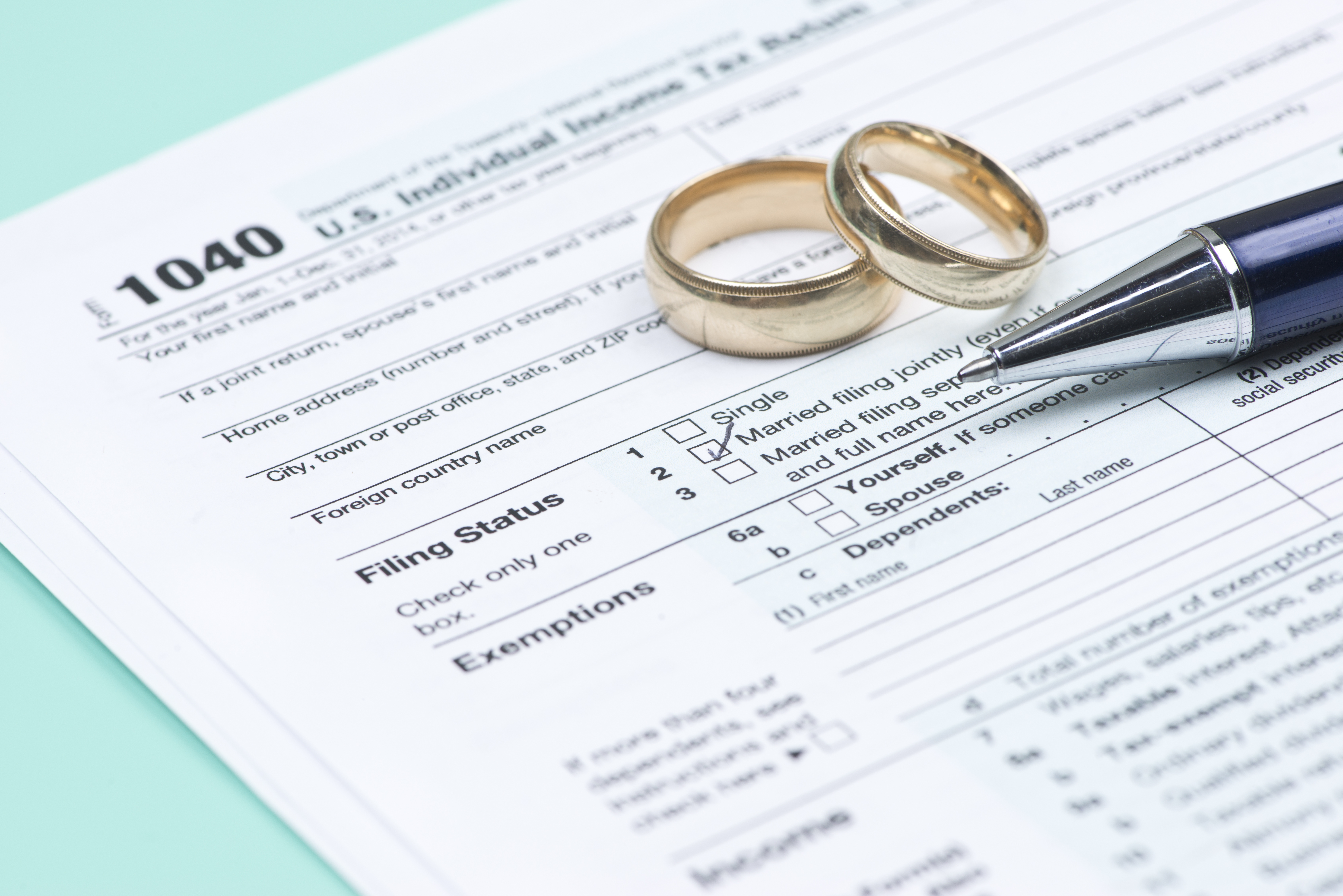 Wedding rings with United states tax form 1040 and pen.